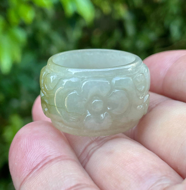 Close-up of continuous hand-carved floral and swirl design on an icy apple green and spinach green Burmese jade ring