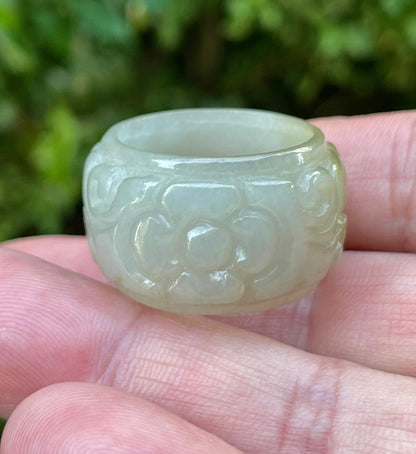 Close-up of continuous hand-carved floral and swirl design on an icy apple green and spinach green Burmese jade ring