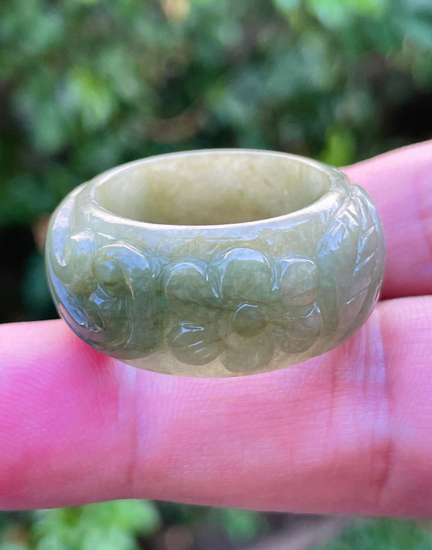 Close-up of flowing curves and floral details on an earthy mossy green Burmese jade ring