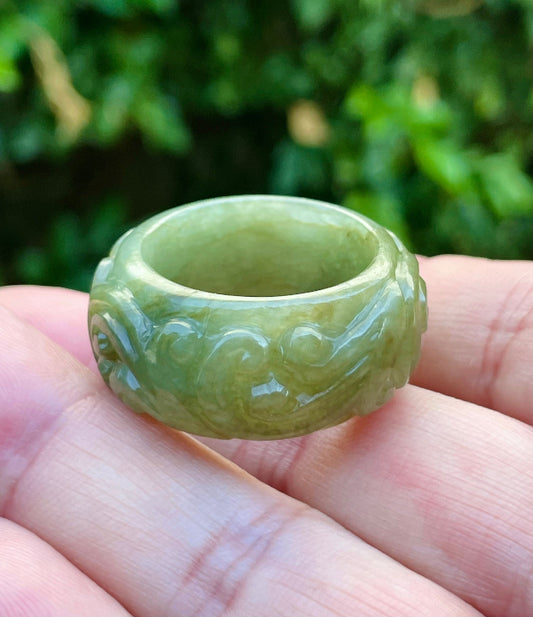 Close-up of flowing curves and floral details on an earthy mossy green Burmese jade ring