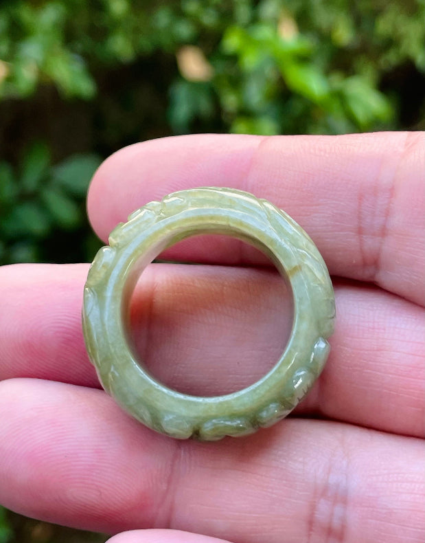 Close-up of flowing curves and floral details on an earthy mossy green Burmese jade ring