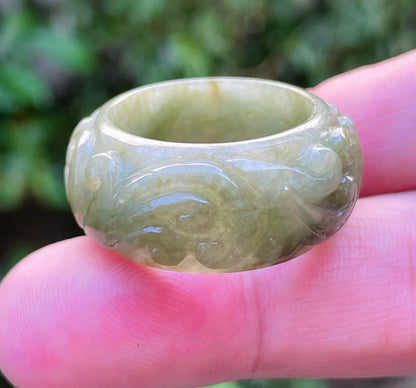 Close-up of flowing curves and floral details on an earthy mossy green Burmese jade ring