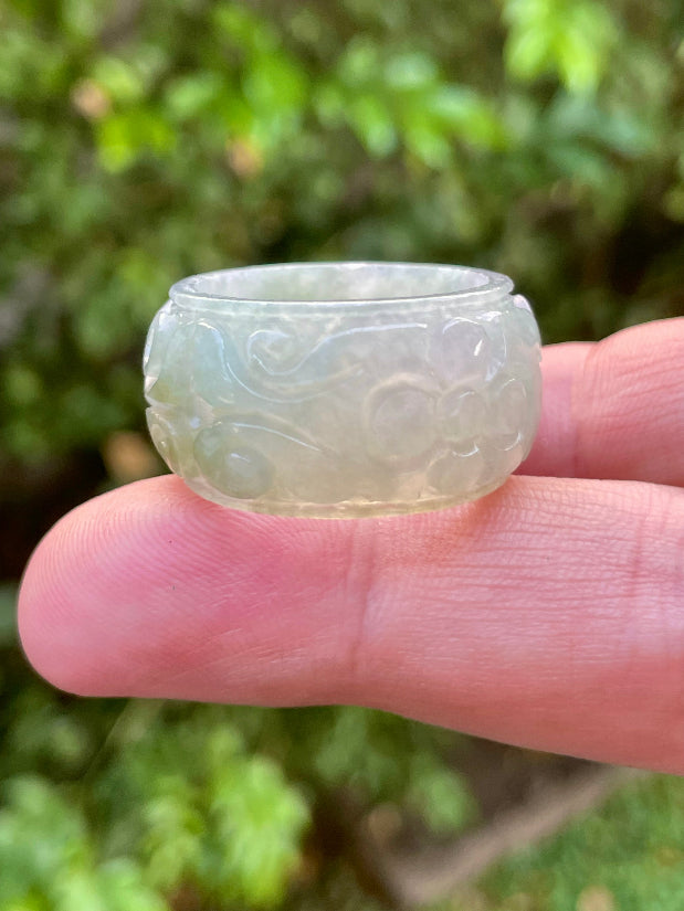 Close-up of skillfully sculpted curves and blooms on an icy white and imperial green Burmese jade ring