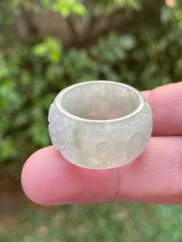 Close-up of skillfully sculpted curves and blooms on an icy white and imperial green Burmese jade ring