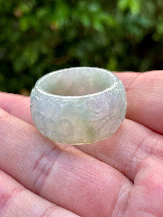 Close-up of skillfully sculpted curves and blooms on an icy white and imperial green Burmese jade ring