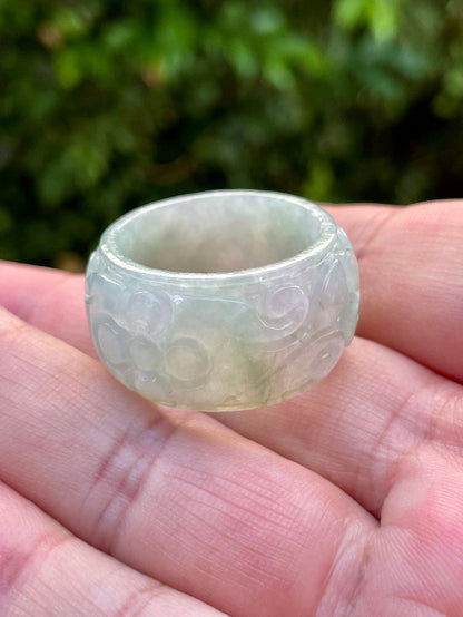 Close-up of skillfully sculpted curves and blooms on an icy white and imperial green Burmese jade ring