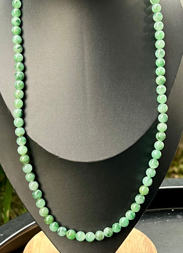Woman wearing a 23-inch elegant natural Grade A jade bead necklace with a gold-tone twist clasp