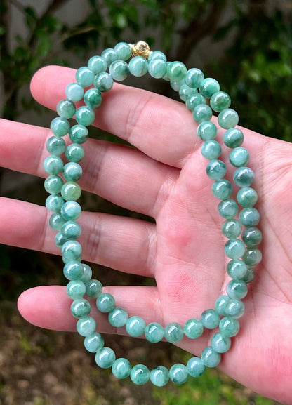 Woman wearing a 23-inch elegant natural Grade A jade bead necklace with a gold-tone twist clasp