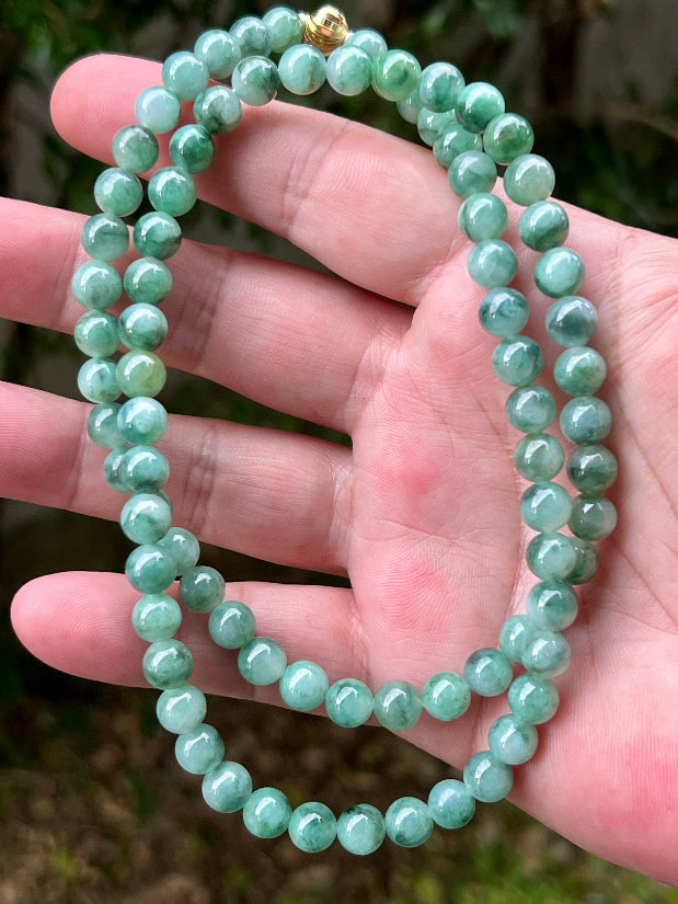 Woman wearing a 23-inch elegant natural Grade A jade bead necklace with a gold-tone twist clasp