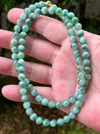 Woman wearing a 23-inch elegant natural Grade A jade bead necklace with a gold-tone twist clasp