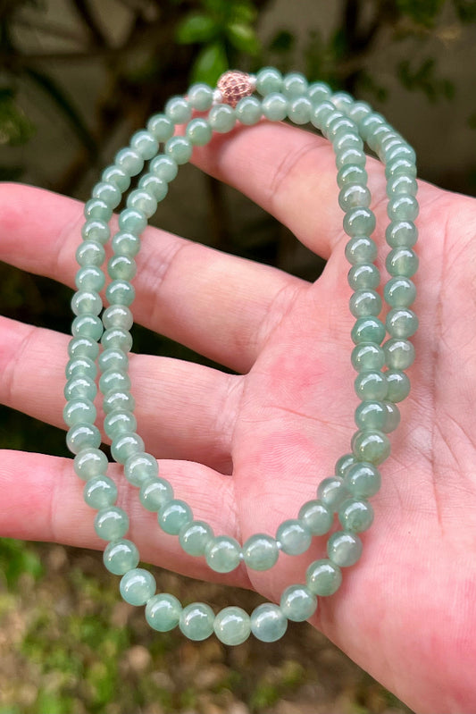 Woman wearing a 23-inch elegant natural Grade A jade bead necklace with a red-tone twist clasp