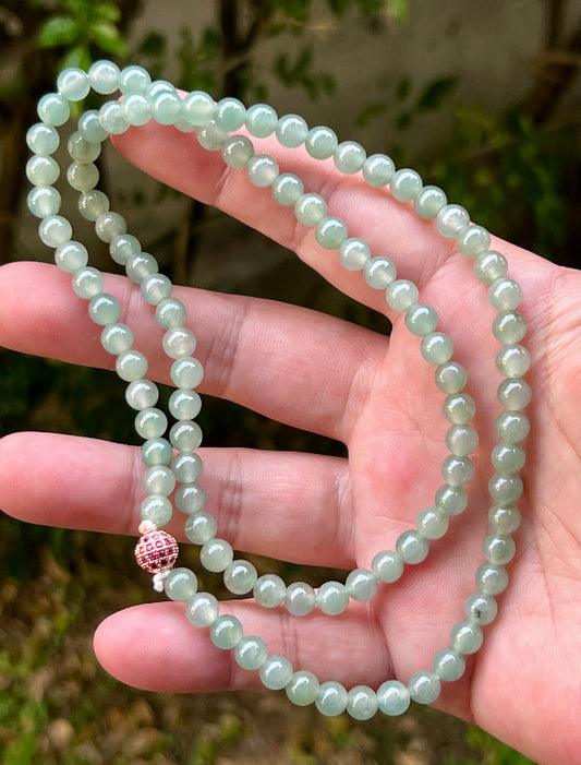 Woman wearing a 23-inch elegant natural Grade A jade bead necklace with a red-tone twist clasp
