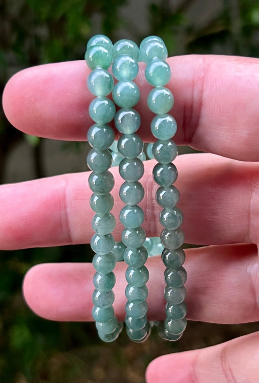 Woman wearing a 23-inch elegant natural Grade A jade bead necklace with a red-tone twist clasp