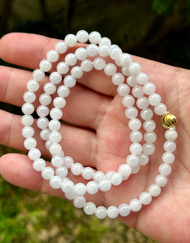 Woman wearing a 23-inch elegant natural Grade A jade bead necklace with a red-tone twist clasp