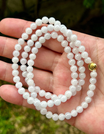 Woman wearing a 23-inch elegant natural Grade A jade bead necklace with a red-tone twist clasp