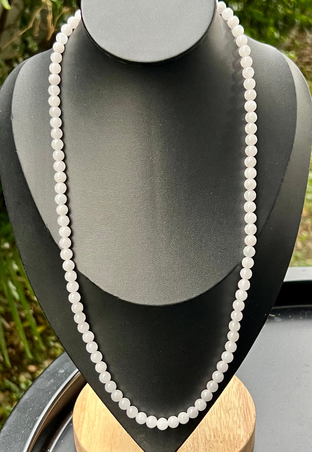 Woman wearing a 23-inch elegant natural Grade A jade bead necklace with a red-tone twist clasp