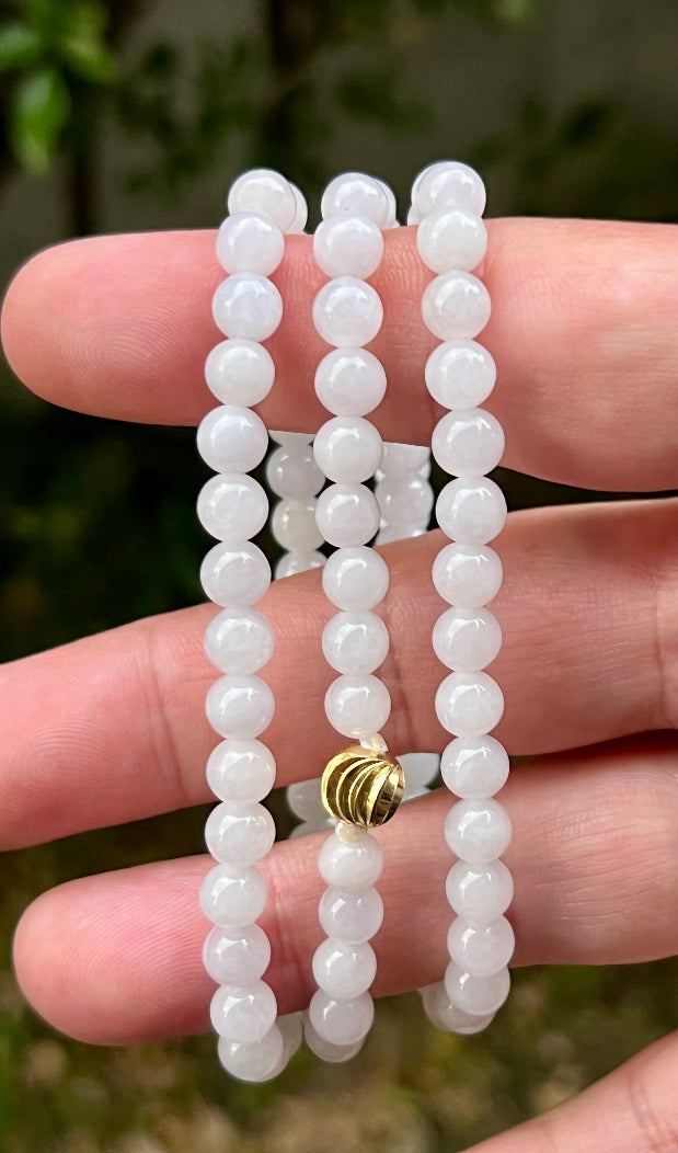 Woman wearing a 23-inch elegant natural Grade A jade bead necklace with a red-tone twist clasp