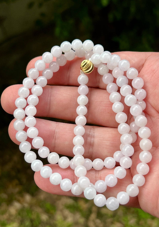 Woman wearing a 23-inch elegant natural Grade A jade bead necklace with a red-tone twist clasp