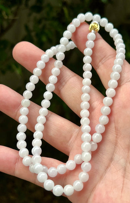 Woman wearing a 23-inch elegant natural Grade A jade bead necklace with a red-tone twist clasp