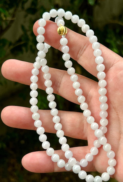Woman wearing a 23-inch elegant natural Grade A jade bead necklace with a red-tone twist clasp