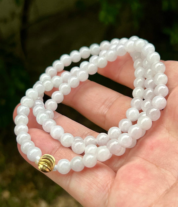 Woman wearing a 23-inch elegant natural Grade A jade bead necklace with a red-tone twist clasp