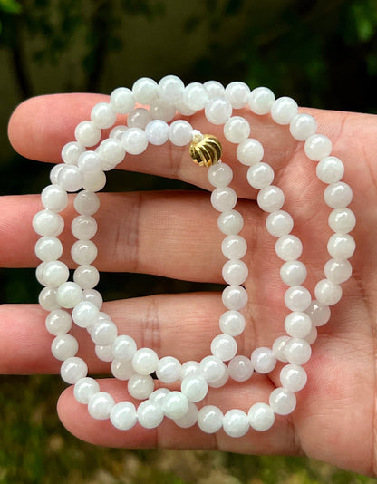 Woman wearing a 23-inch elegant natural Grade A jade bead necklace with a red-tone twist clasp
