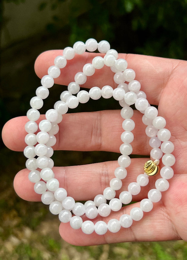 Woman wearing a 23-inch elegant natural Grade A jade bead necklace with a red-tone twist clasp