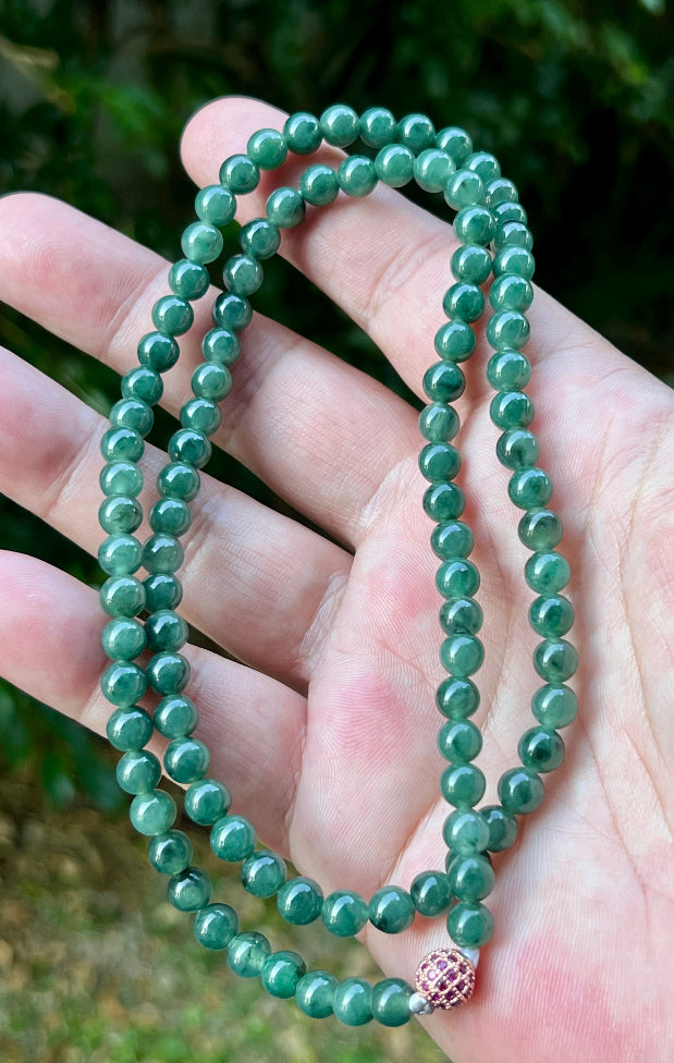 Woman wearing a 22-inch elegant natural Grade A jade bead necklace with a red-tone twist clasp