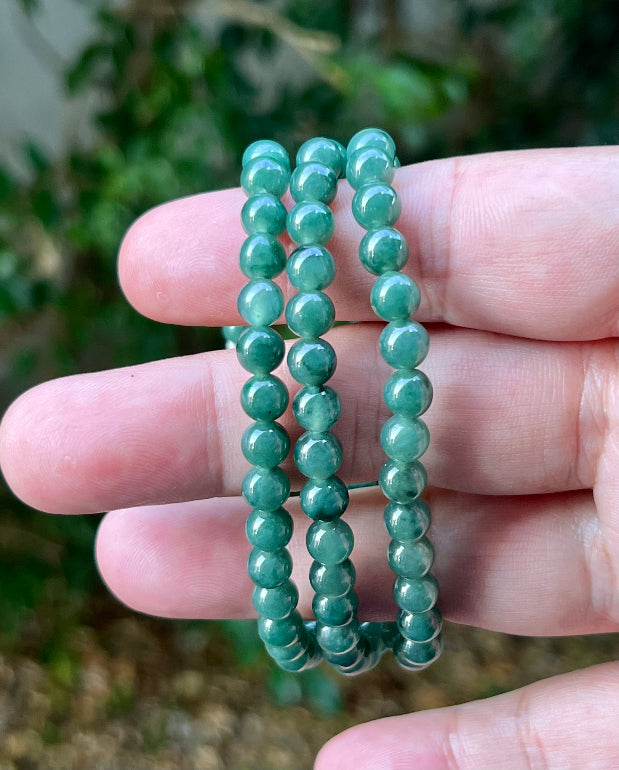Woman wearing a 22-inch elegant natural Grade A jade bead necklace with a red-tone twist clasp