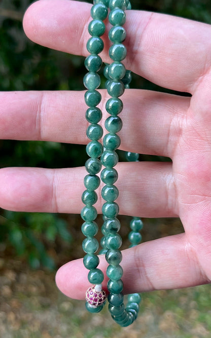 Woman wearing a 22-inch elegant natural Grade A jade bead necklace with a red-tone twist clasp