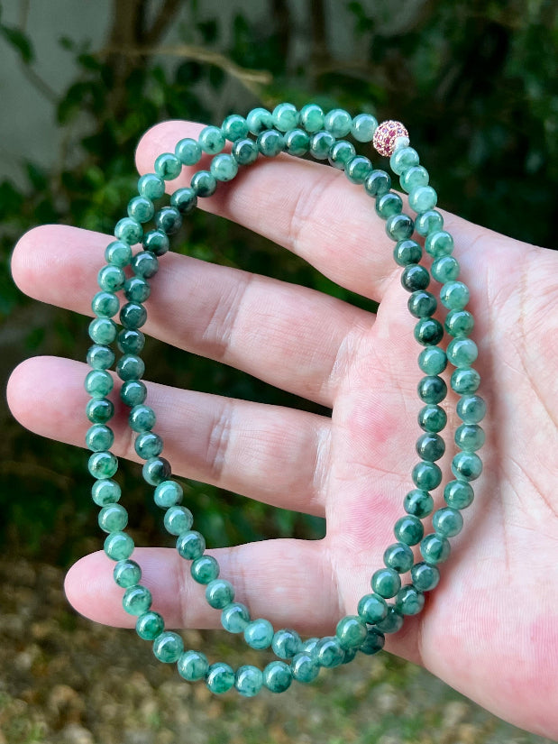 Woman wearing a 22-inch elegant natural Grade A jade bead necklace with a red-tone twist clasp