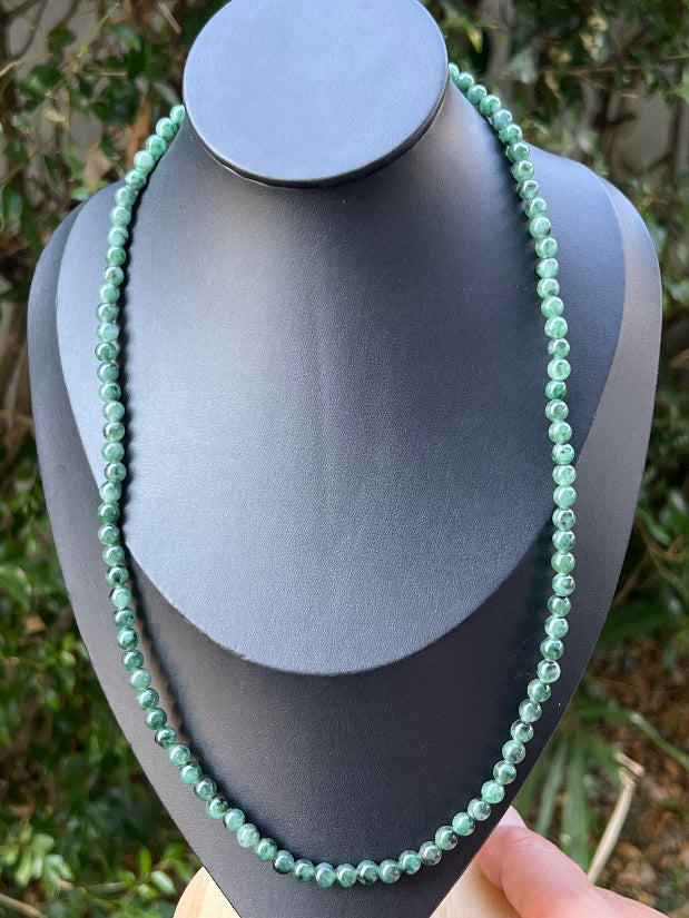 Woman wearing a 22-inch elegant natural Grade A jade bead necklace with a red-tone twist clasp