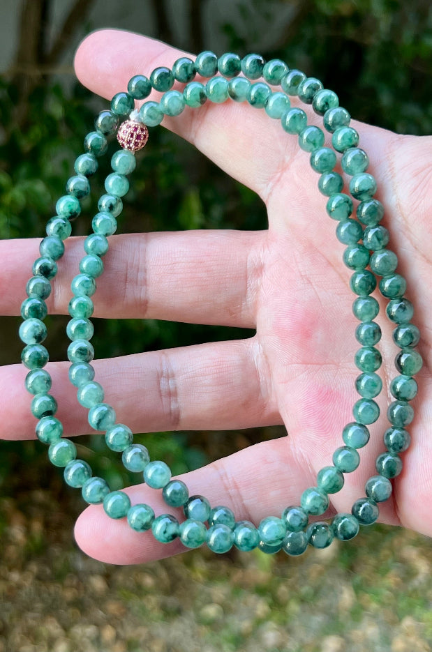 Woman wearing a 22-inch elegant natural Grade A jade bead necklace with a red-tone twist clasp