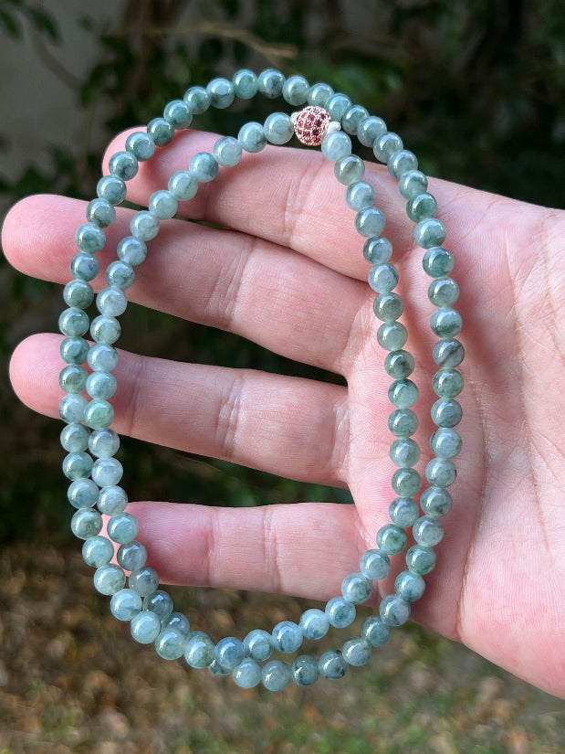 Woman wearing a 22-inch elegant natural Grade A jade bead necklace with a red-tone twist clasp