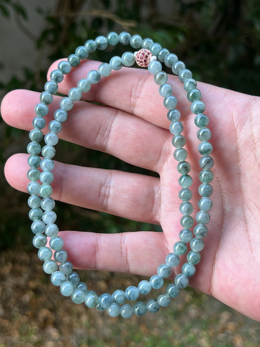 Woman wearing a 22-inch elegant natural Grade A jade bead necklace with a red-tone twist clasp