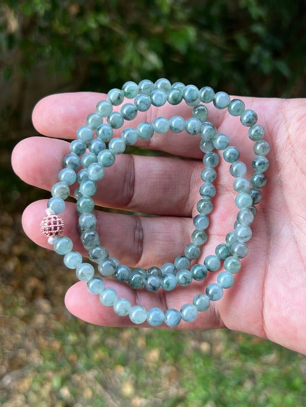 Woman wearing a 22-inch elegant natural Grade A jade bead necklace with a red-tone twist clasp
