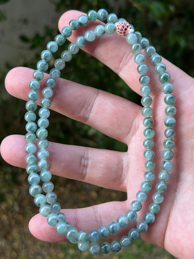 Woman wearing a 22-inch elegant natural Grade A jade bead necklace with a red-tone twist clasp