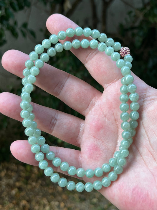 Woman wearing a 23-inch elegant natural Grade A jade bead necklace with a red-tone twist clasp