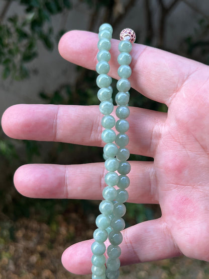 Woman wearing a 23-inch elegant natural Grade A jade bead necklace with a red-tone twist clasp