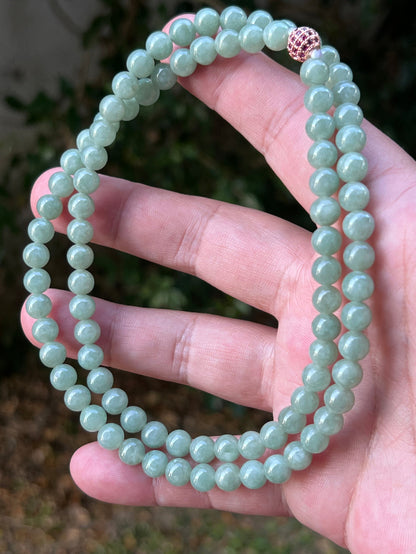 Woman wearing a 23-inch elegant natural Grade A jade bead necklace with a red-tone twist clasp