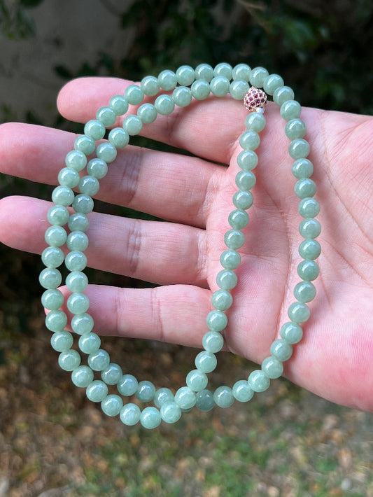 Woman wearing a 23-inch elegant natural Grade A jade bead necklace with a red-tone twist clasp