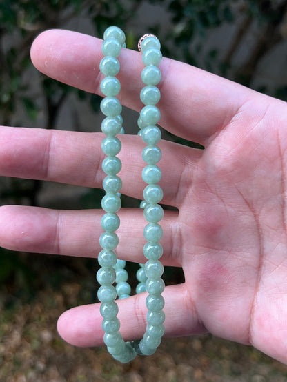Woman wearing a 23-inch elegant natural Grade A jade bead necklace with a red-tone twist clasp