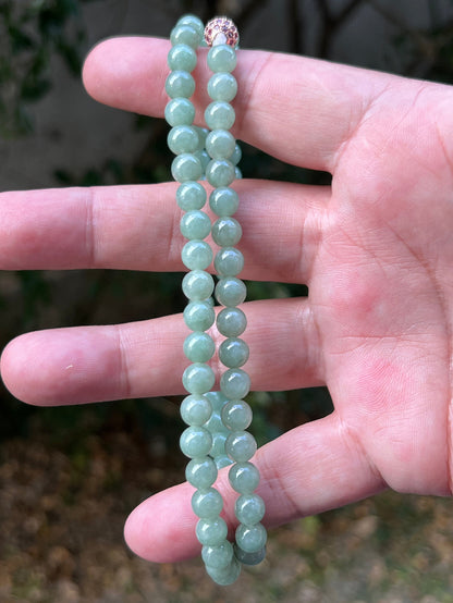 Woman wearing a 23-inch elegant natural Grade A jade bead necklace with a red-tone twist clasp