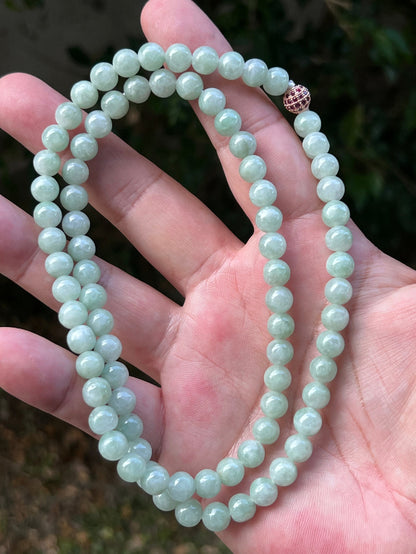 Woman wearing a 22-inch elegant natural Grade A jade bead necklace with a red-tone twist clasp