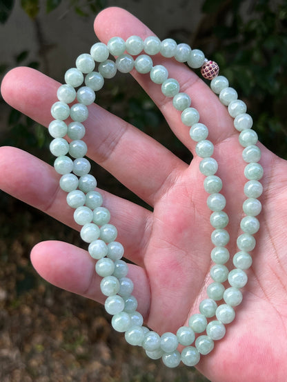 Woman wearing a 22-inch elegant natural Grade A jade bead necklace with a red-tone twist clasp
