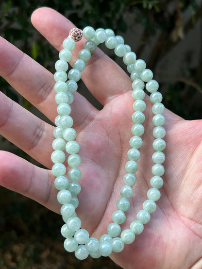 Woman wearing a 22-inch elegant natural Grade A jade bead necklace with a red-tone twist clasp