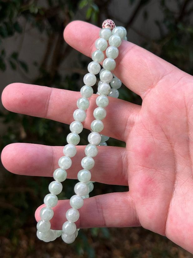 Woman wearing a 22-inch elegant natural Grade A jade bead necklace with a red-tone twist clasp
