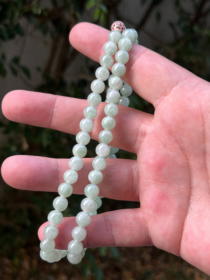 Woman wearing a 22-inch elegant natural Grade A jade bead necklace with a red-tone twist clasp