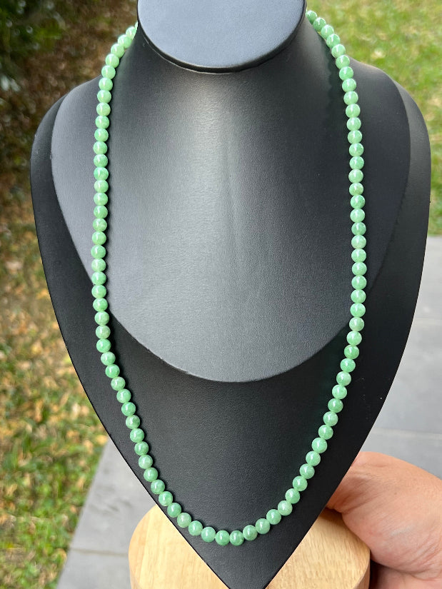 Woman wearing a 23-inch elegant natural Grade A jade bead necklace with a gold-tone twist clasp