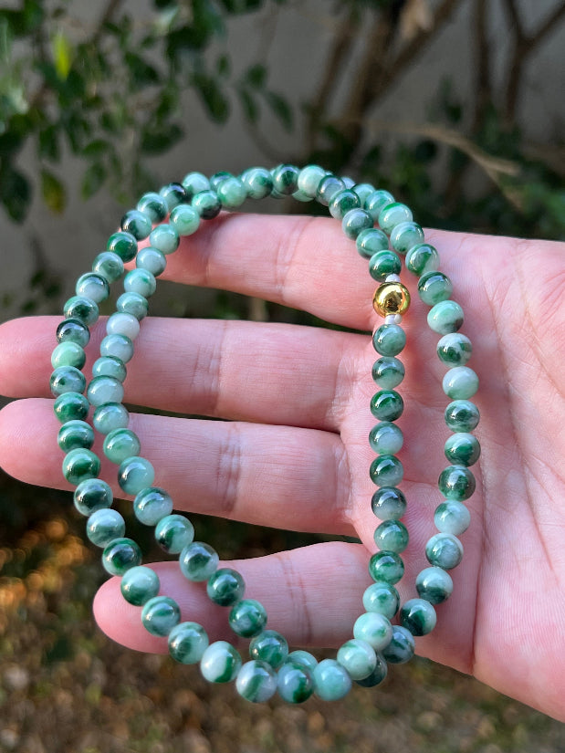 Woman wearing a 22-inch elegant natural Grade A jade bead necklace with a gold-tone twist clasp